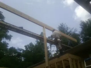 Carpenter setting a ridge beam over a new addition frame — Ice Dam Removal by Roofing Brothers in Crowley